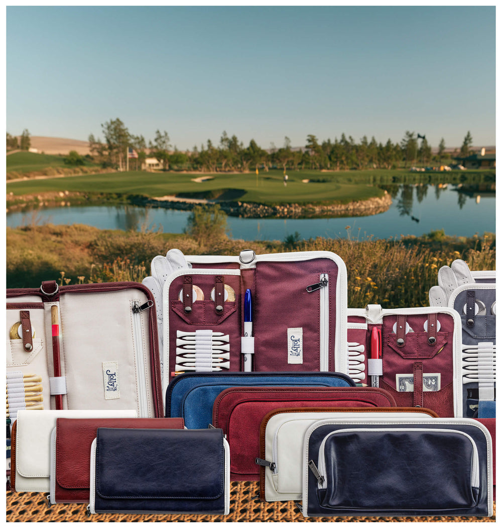 A collection of golf accessory pouches and organizers in maroon, navy, blue, cream, and white, arranged on a woven mat in front of a golf course landscape with water and green fairways.